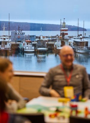 workshop participants in a room with a view of lake and boats on the background