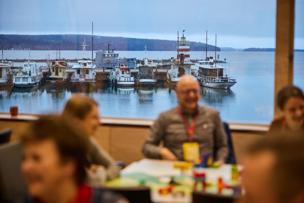 workshop participants in a room with a view of lake and boats on the background