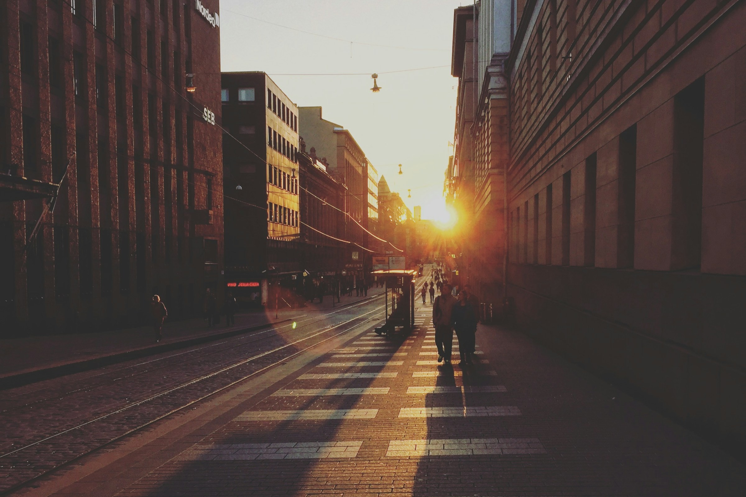 two people walking between concrete buildings towards sunshine